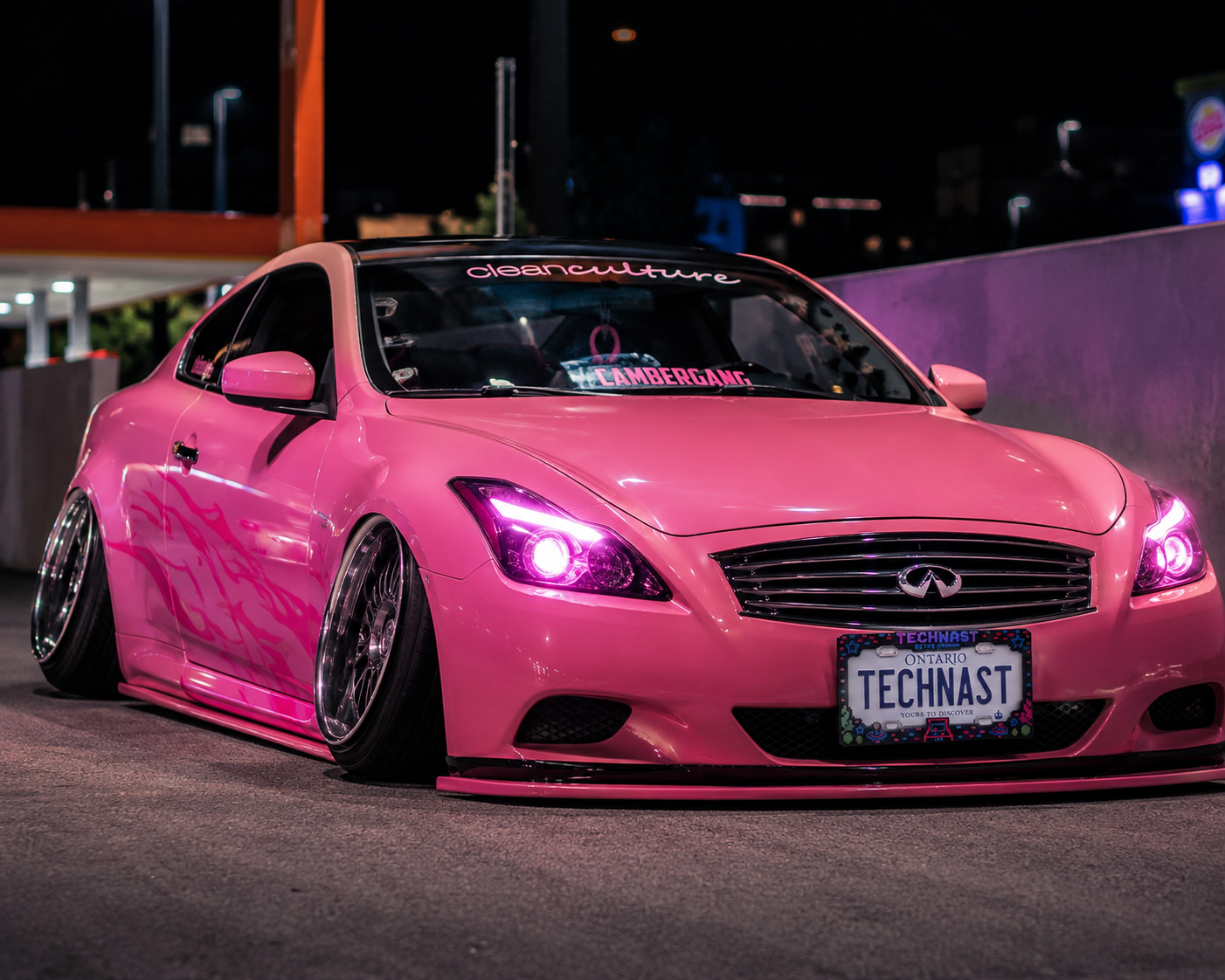 Wide night view of a pink custom car wearing the TECHNAST Retro Arcade license plate frame.